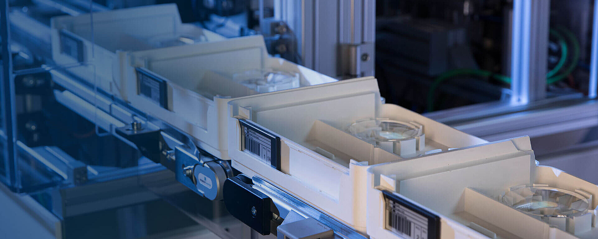 Trays with Satisloh E-ticket tags on a conveyor system.