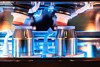 Close-up of dual polishing tools processing glass lenses inside an industrial machine.