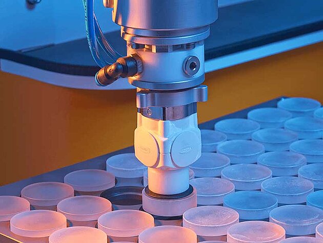 Close-up of robotic arm placing components into circular slots on a tray