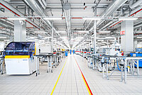 Bright modern factory floor with industrial machines, equipment, and organized workstations.