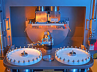 Close-up of a Satisloh SPM-10 with optional HS-30 handling system for lens processing in precision optics.
