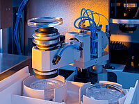 Automated machine precisely placing glass lenses into holders during the manufacturing process.