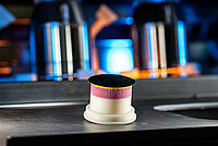 Close-up of a polishing tool inside an industrial lens processing machine.