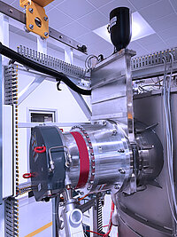 Close-up of industrial semiconductor equipment with metallic piping, connectors, and processing chamber.