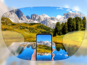 View through a pair of glasses showing a clear landscape with mountains, trees, and a lake, with a smartphone held in the center capturing the same scene.
