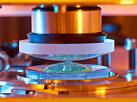 Close-up of a precision manufacturing process where a lens or glass component is being processed in a machine
