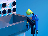Close-up of a cleaning station with spray nozzles and connectors on an industrial machine.
