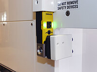 Close-up of a safety interlock system with indicator light mounted on industrial equipment.