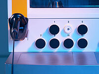 Close-up of a machine control panel with multiple round buttons and connectors.