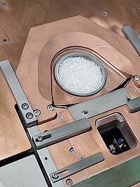 Close-up of machine interior with circular chamber containing white granules and metal components
