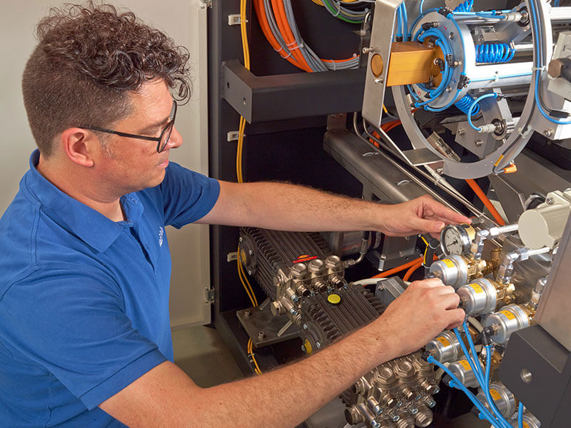 Technician adjusting cables and components inside an industrial machine
